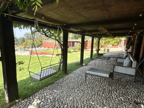 Patio cubierto con cama columpio colgante, tumbonas y piso de piedra en villa Casa Las Cuadras, Candeleda
