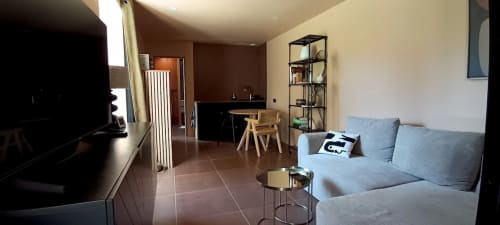 Le gîte La Garçonnière au Domaine Alga à Bourg-Charente offre un espace de vie moderne avec canapé, télévision, bureau et vue sur le jardin