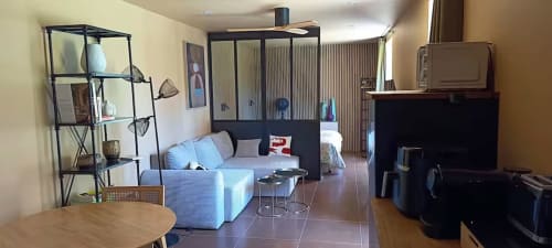 Séjour cottage moderne à Domaine Alga avec canapé bleu, TV, bureau et vue sur le jardin à Bourg-Charente