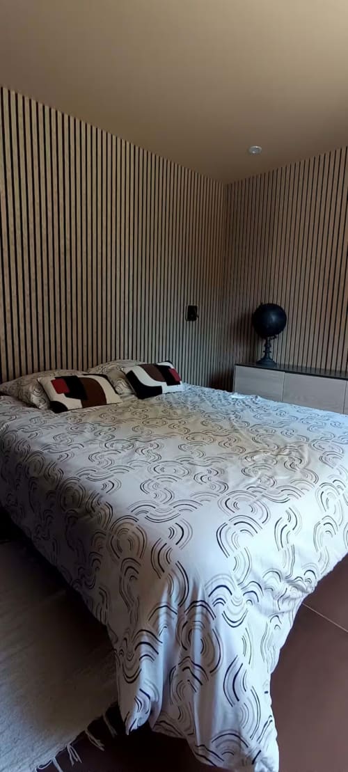 Chambre moderne du gîte Domaine Alga à Bourg-Charente avec mur d'accent rayé, literie à motifs et coussins de décoration
