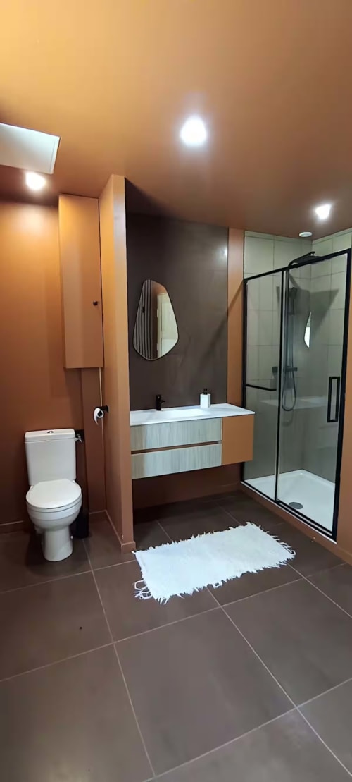 Salle de bain moderne du gîte Domaine Alga avec lavabo, toilettes, douche à l'italienne et éclairage chauffant