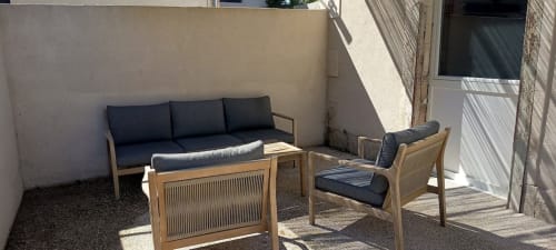 Coin terrasse extérieur du gîte Domaine Alga avec mobilier en bois et coussins foncés à Bourg-Charente