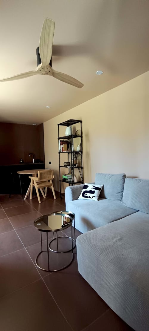 Salon moderne au Domaine Alga avec ventilateur de plafond, canapé bleu ciel, table d'appoint ronde et espace bureau en bois