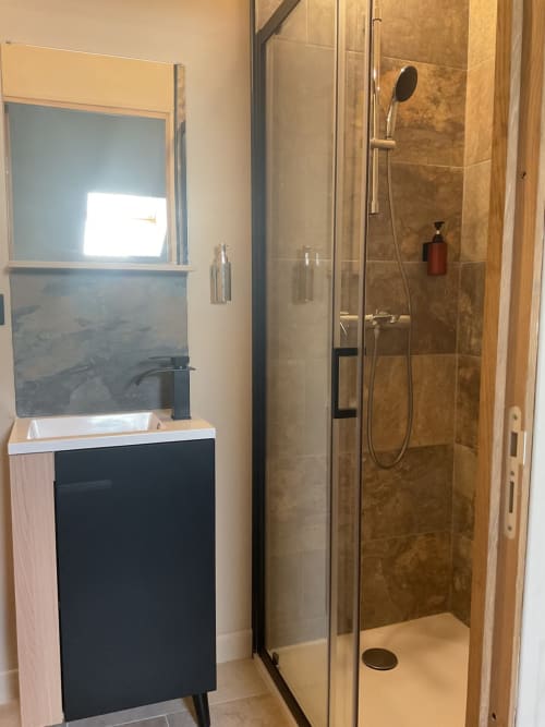 Salle de bain moderne du gîte Domaine Alga avec douche vitrée, vasque et radiateur-sèche-serviettes