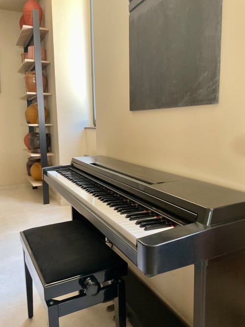 Piano numérique avec banc noir dans la salle de musique du gîte Domaine Alga, Bourg-Charente, avec rangement pour instruments