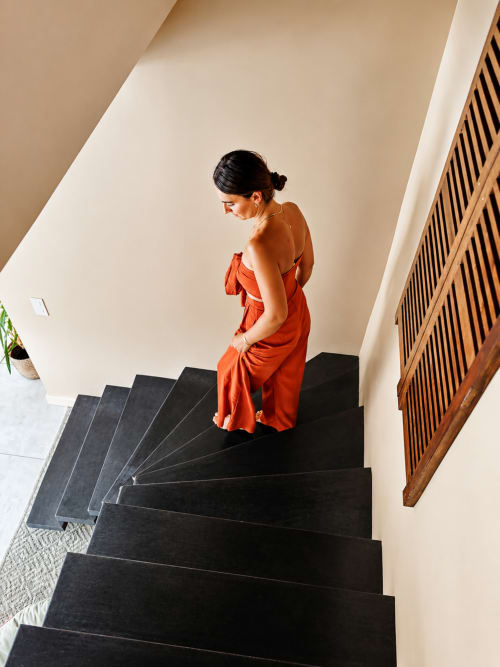 Femme enceinte en robe orange descendant l'escalier noir de La Maison d'Ambrine, CHAMARET