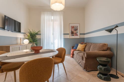 Appartamento famiglia Terrestre Roma con tavolo da pranzo, divano marrone, TV e pareti moderne a righe blu