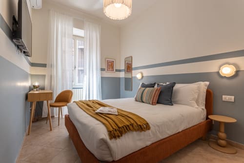 Camera moderna al Terrestre Roma BnB con letto in legno, parete a righe, zona lavoro e vista sulla città dalla finestra