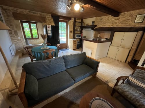 Séjour chaleureux avec canapé sombre au Gîte La Vieille Ferme, Saint-Geniès, murs en pierre et cuisine