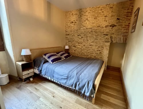 Chambre douillette du Gîte La Vieille Ferme de La Dounie avec lit en bois, linge bleu et mur de briques rustique, Saint-Geniès