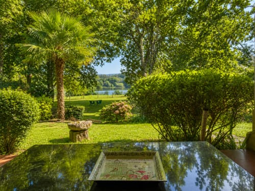 Vistas exuberantes del jardín de la casita As Landras en Tomiño con el río Miño visible entre árboles y plantas en flor