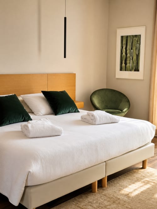 Chambre moderne à La Maison D'ambrine avec tête de lit en bois, literie blanche, coussins verts et décor minimaliste à Chamaret