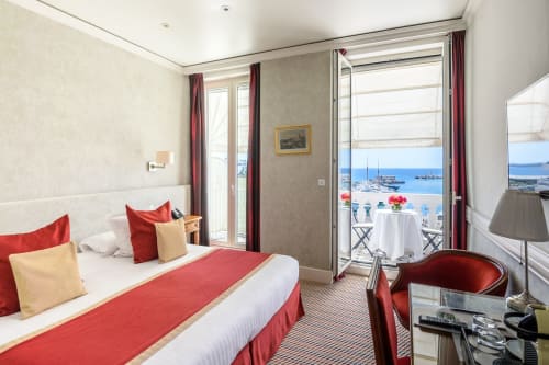 Chambre luxe à l'Hôtel Splendid Cannes avec balcon vue mer, accents rouges et panorama du port méditerranéen