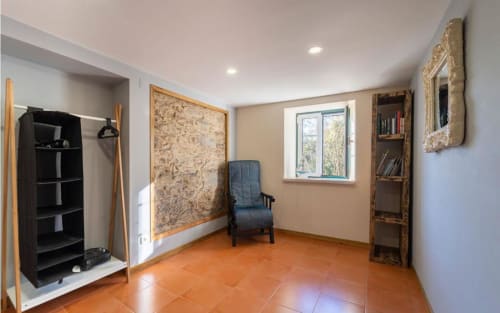 Spacious room at Quinta Boa Vida with orange tile flooring, blue chair, wooden shelving, and garden views in Alcobaça