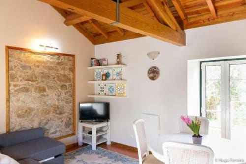 Modern living room at Quinta Boa Vida villa in Alcobaça with exposed wooden beams, TV, shelving, and garden view doors