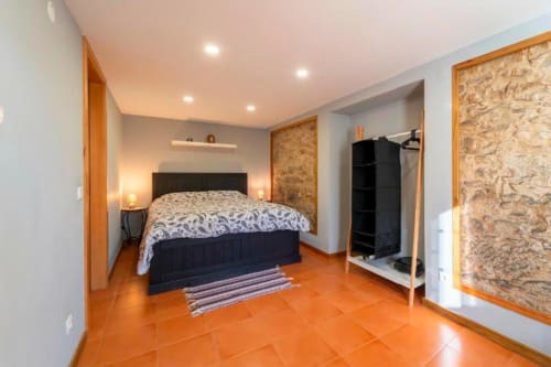 Modern bedroom at Quinta Boa Vida villa in Alcobaça with black bed, orange tile flooring, and cork wall accents