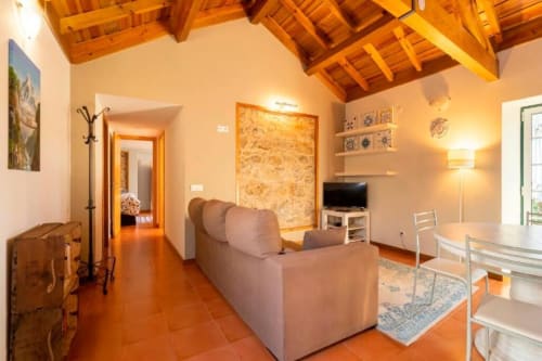 Spacious living room at Quinta Boa Vida villa in Alcobaça with wooden beams, terracotta floors, comfortable sofa, TV, and