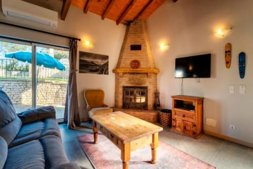 Spacious living area in Master Villa at Quinta Boa Vida, Alcobaça with fireplace, wooden beams, TV, and garden views through