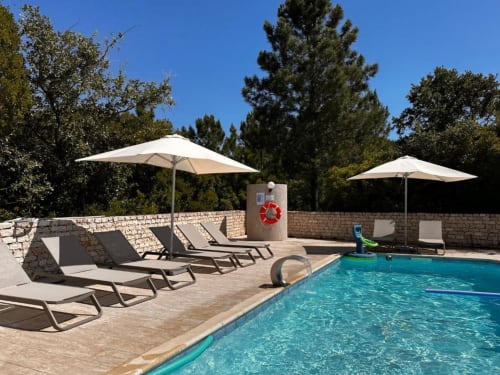 Swimming pool at Quinta Boa Vida in Alcobaça with loungers, umbrellas, stone walls and garden views