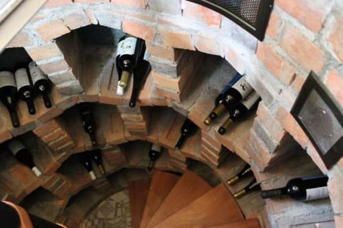 Wine cellar with brick archway and wine bottles stored in wooden racks at Quinta Boa Vida, Alcobaça