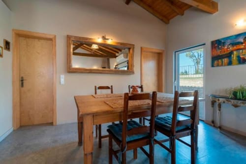 Dining room at Quinta Boa Vida villa in Alcobaça with wooden table, chairs, exposed beams, and garden view through glass