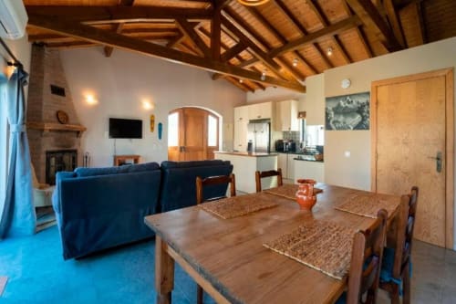 Open-plan dining and living area at Quinta Boa Vida villa in Alcobaça with wooden beams, fireplace, and garden views