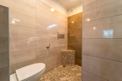Modern bathroom with walk-in shower, beige tile walls, and stone accent in Quinta Boa Vida master villa, Alcobaça