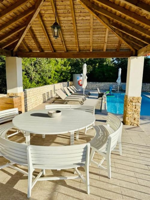 Luxury poolside terrace at Quinta Boa Vila with white dining furniture, wooden pergola, and blue pool in Alcobaça.