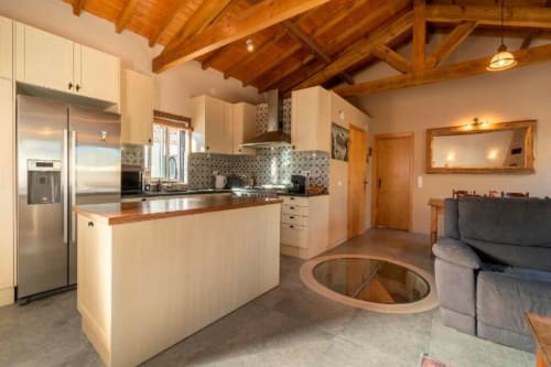 Open-plan kitchen and living area with cream cabinetry, wooden beams, and modern stainless steel appliances at Quinta Boa