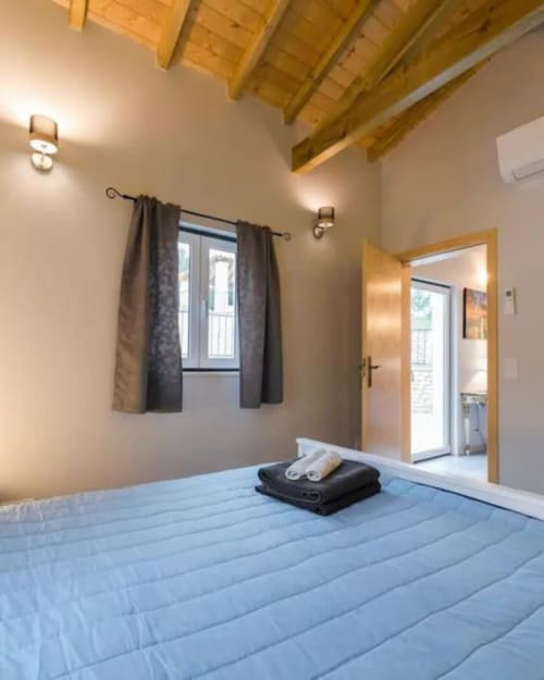 Bright bedroom at Quinta Boa Vida in Alcobaça with blue bedding, wooden beams, window, and garden view door