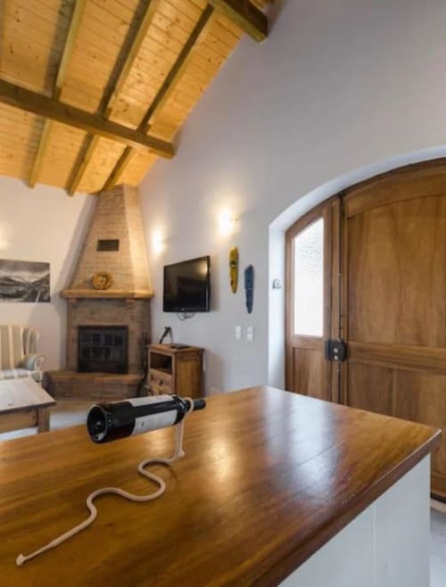Modern living room with wooden beams, fireplace, dining table, and wine bottle at Quinta Boa Vida villa in Alcobaça