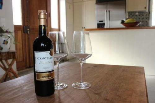 Cancellus wine bottle with two empty glasses on wooden table in Quinta Boa Vida master villa, Alcobaça