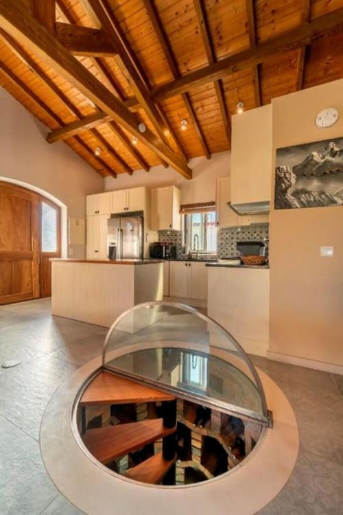Modern kitchen with exposed wooden beams and circular wine cellar opening at Quinta Boa Vida villa in Alcobaça