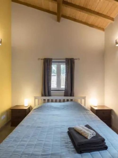 Bright bedroom with blue bedding and rolled towels at Quinta Boa Vida villa in Alcobaça, Portugal, featuring wooden beams and