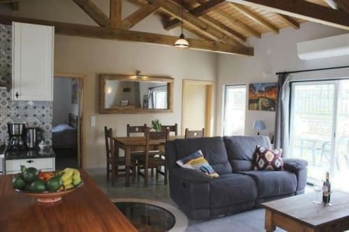 Open-plan living area at Quinta Boa Vida villa with blue sofa, dining table, wooden beams, and garden views in Alcobaça
