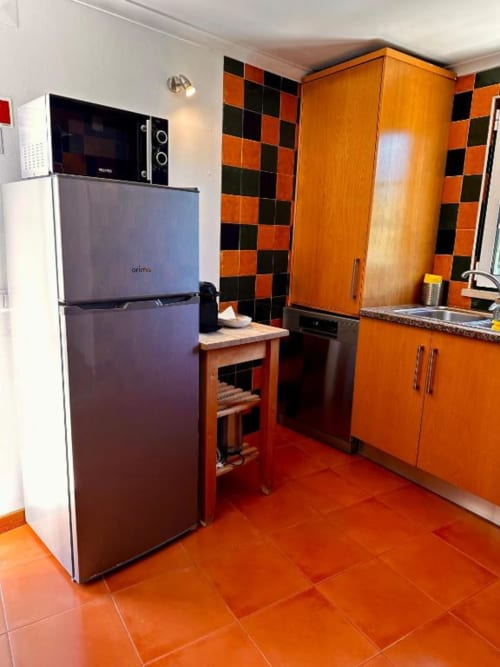 Modern kitchen with orange cabinetry, stainless steel appliances, and checkered backtile at Quinta Boa Vida in Alcobaça