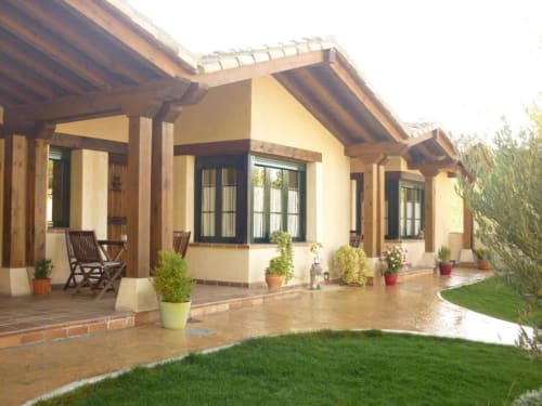 Terraza de La Senda del Duratón con pérgola de madera, plantas en macetas y jardín bien cuidado en Sebúlcor
