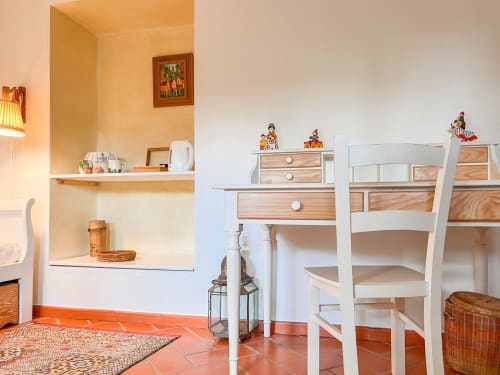 Quarto luminoso da Quinta da Mata de Baixo com mobiliário branco, escrivaninha de madeira, piso em azulejo terracota e vista para o jardim