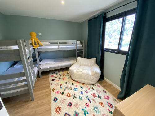 Chambre d'enfants avec lits superposés, fauteuil poire, tapis coloré et portes-fenêtres à la villa CASA DI SADREA à Lecci