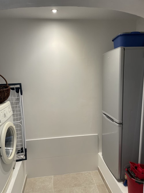 Buanderie moderne avec lave-linge blanc, réfrigérateur en acier inoxydable et carrelage au gîte Les Pratges