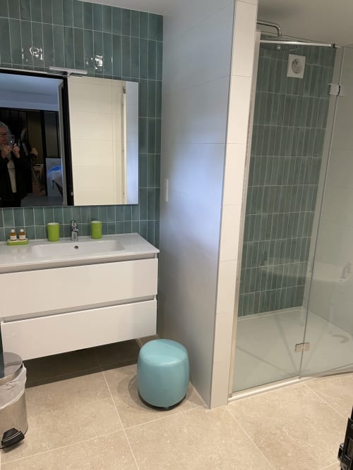 Salle de bain moderne avec carrelage vert, vasque blanche, douche pluie et sol en carrelage clair aux Pratges à Figeac
