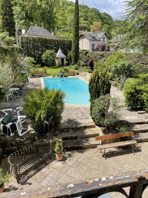 Piscine bleu scintillant entourée de jardins luxuriants et terrasse en pierre aux Chambres d'hôtes Les Pratges à Figeac