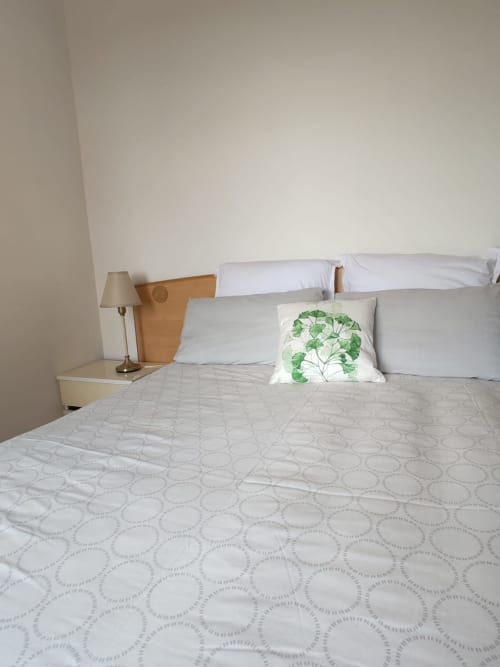Chambre Armonia de l'Hôtel Allegria à Bajardo avec literie blanche, coussin à motifs feuillage et vue sur les montagnes