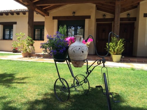 Macetero de hierro forjado decorativo con vasijas de cerámica en el patio del jardín de La Senda del Duratón