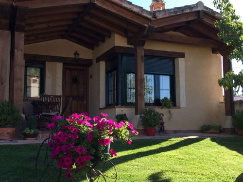 Casa La Senda del Duraton en Sebúlcor con petunias magenta, vigas de madera y jardín manicurado