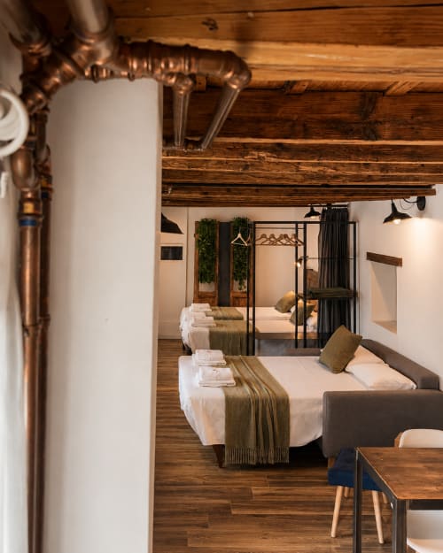 Modernes Loft-Schlafzimmer in Apartments Borgovivobg Bergamo mit Holzbalken, mehreren Betten, schwarzen Metallrahmen und Industrie-Design