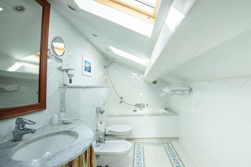 Bagno moderno nella suite mansardata dell'Hotel Splendid Cannes con lucernario, lavabo in marmo, bidet e piastrelle decorative