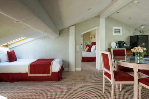 Suite Mansard dell'Hotel Splendid Cannes con letti gemelli, accenti rossi e zona living open-plan