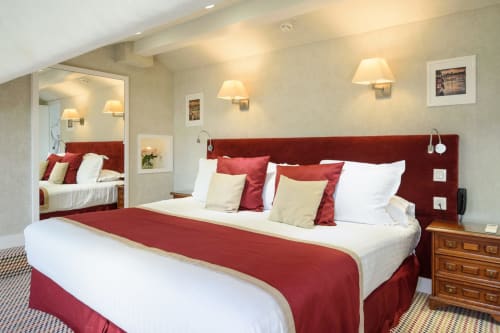 Suite familiare di lusso all'Hotel Splendid Cannes con testata bordeaux, biancheria bianca, cuscini color crema e