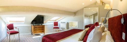Suite mansardata di lusso all'Hotel Splendid Cannes con letto king, accenti rossi, lucernario e servizi moderni
